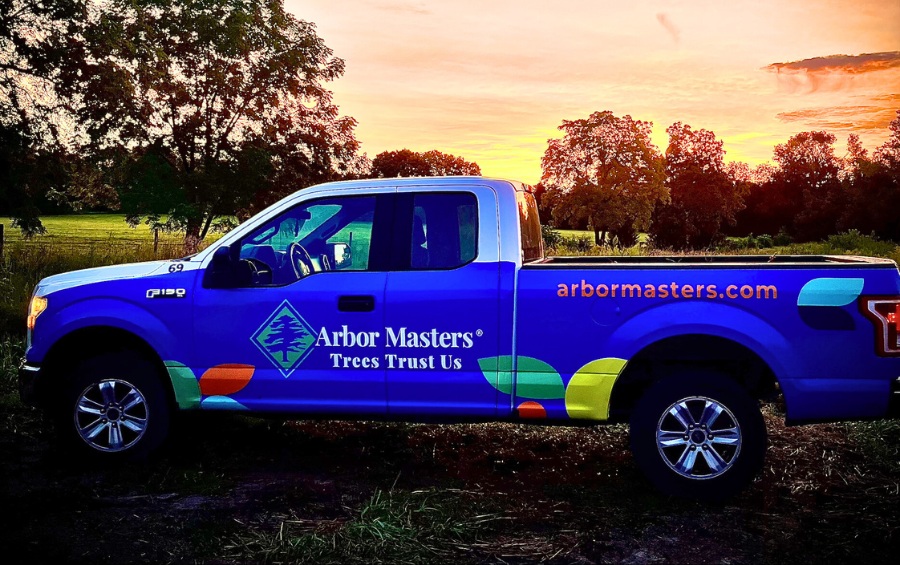 Arbor Masters tree service truck in Des Moines at sunset, showcasing company branding and commitment to professional tree care.