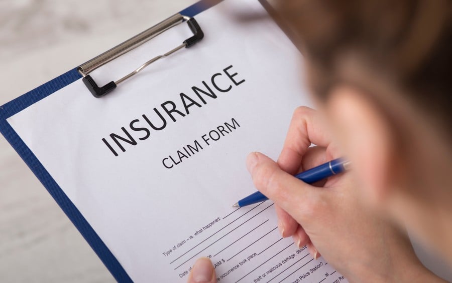 Person completing an insurance claim form after property damage, documenting information for a homeowners insurance claim.