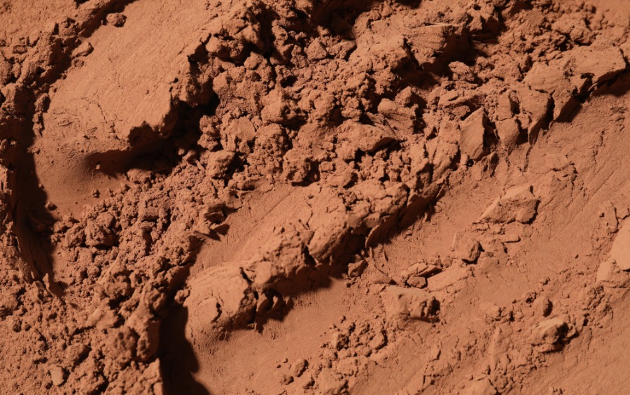 Dry, cracked clay soil broken into rough chunks and fine powder, showing the dense, compacted texture typical of North Texas ground during drought.