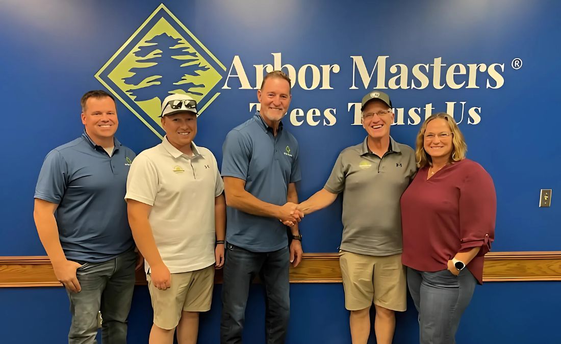 Arbor Masters and TreeHugger owners shake hands in front of the Arbor Masters logo, marking their new partnership to strengthen Central Iowa tree care.