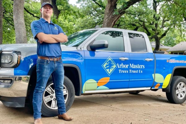 Arbor Masters arborist standing beside branded truck — professional tree care services in Arlington, TX