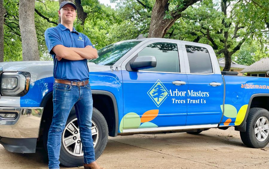 An arborist from Arbor Masters stands in front of a truck in Grand Prairie, TX