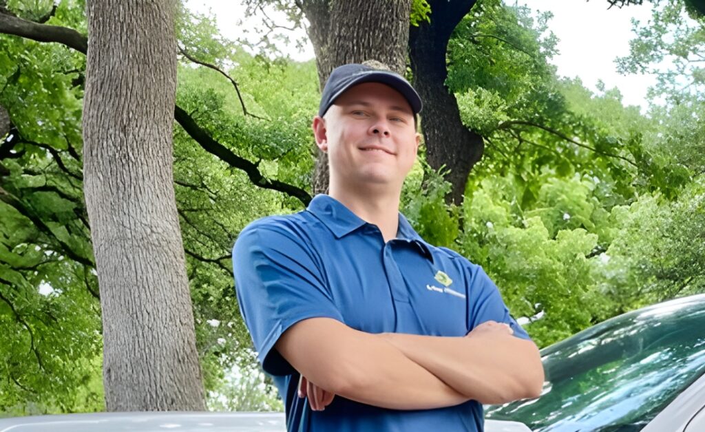 A confident Arbor Masters arborist stands next to the company truck after completing a professional tree assessment.