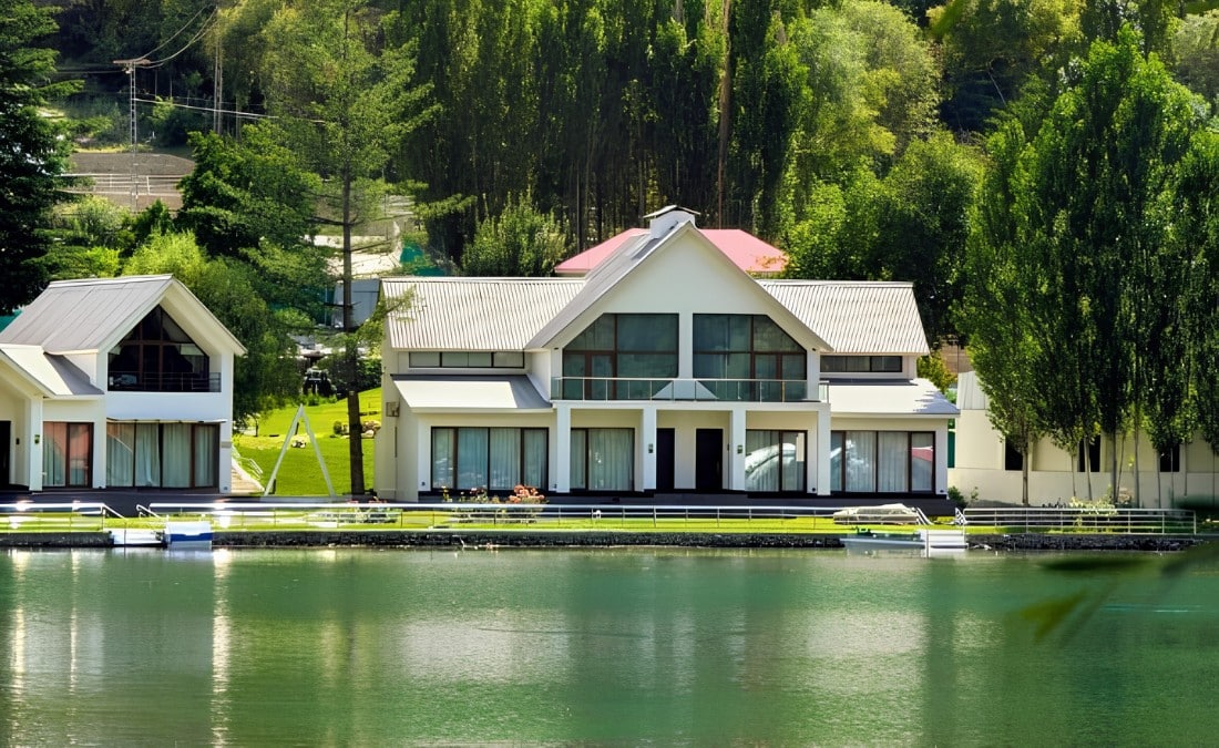Lakefront estate framed by mature trees, with the home and dock mirrored in calm water.