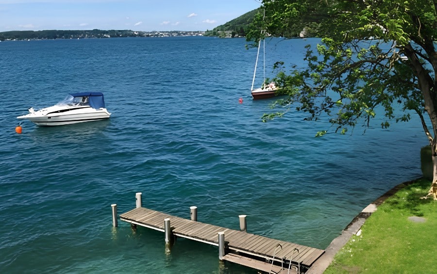 Mature tree branches extending out over a wooden dock and moored boats on a Lee's Summit lakefront