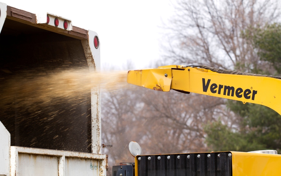 A Vermeer wood chipper processing cleared vegetation debris during an Oklahoma City lot clearing project.