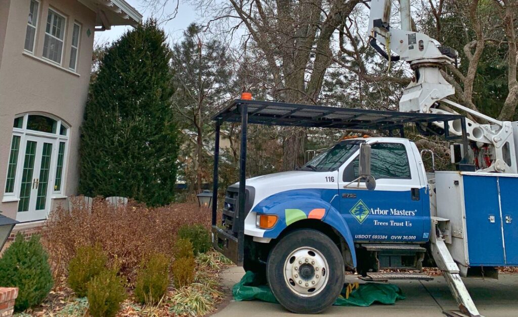 Arbor Masters bucket truck positioned for winter tree pruning near a Johnson County, Kansas home.