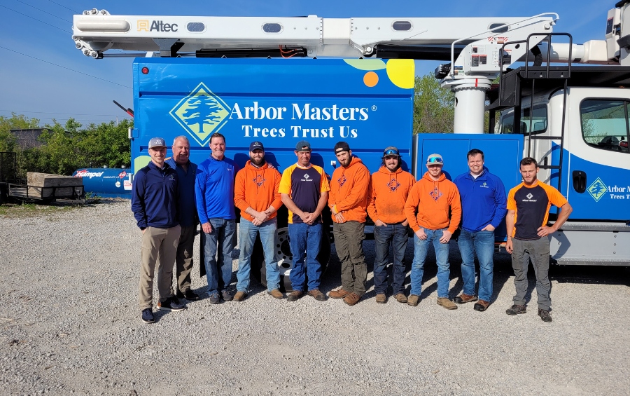 Arbor Masters tree service crew standing in front of branded bucket truck, providing professional pruning in Shawnee, Kansas.