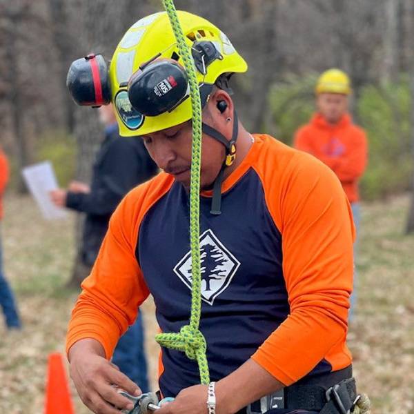 An arborist of Arbor Masters prearing his harness before doing tree work.