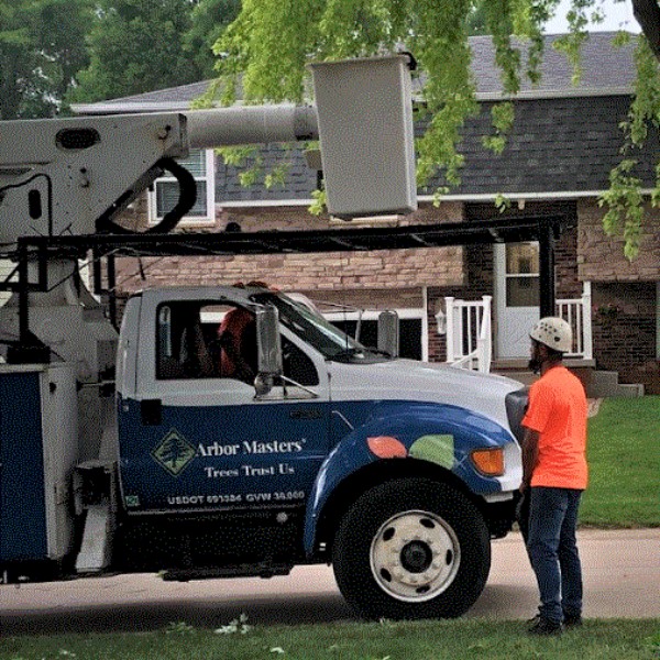 Website-DM-pruning-section-bucket-truck-guy arborist beside the Arbor Masters bucket truck, preparing for a tree trimming.