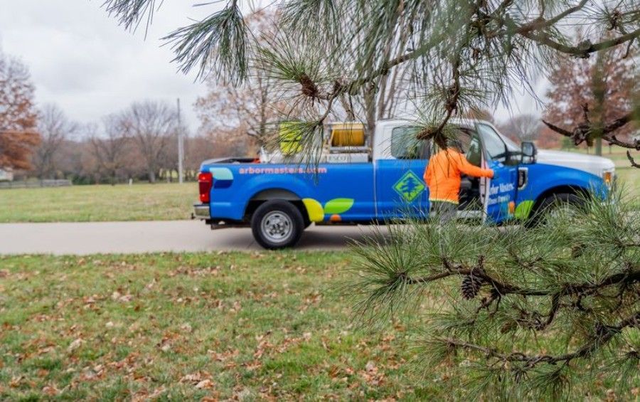 Arbor Masters plant health care service truck parked beside mature shade trees.