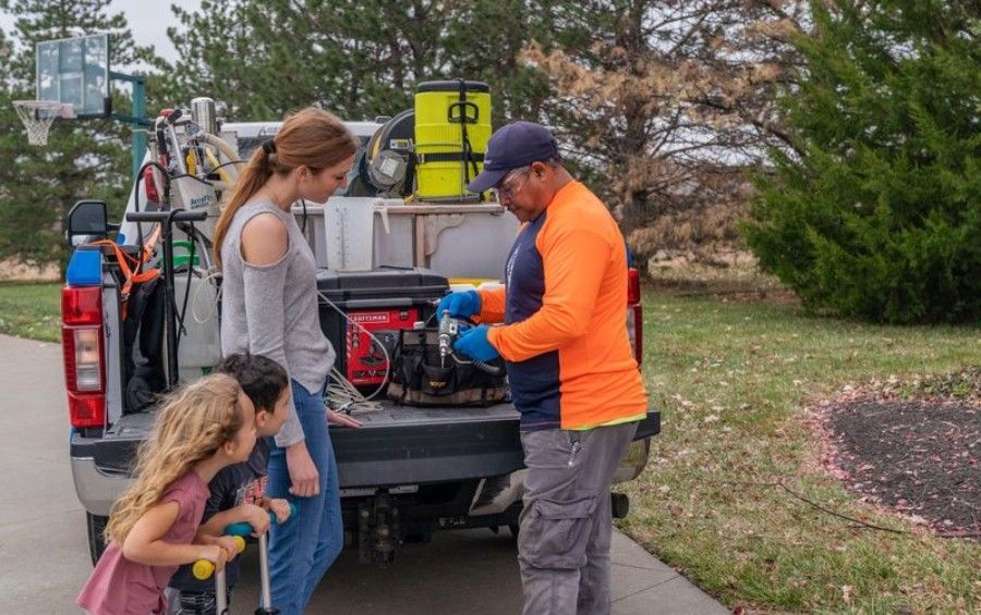 Arbor Masters plant health care technician discussing tree health and treatment options with a Dallas homeowner beside a service truck.